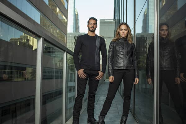 A young modern-looking man and women wear sleek black clothes from the Harley-Davidson H-D Moto Collection.