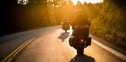 Two motorcyclists riding their Harley-Davidson motorcycles on a sunny day.